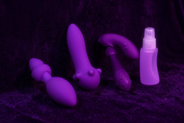 アナルプラグと振動バイブが暗めのテーブルに並んでいるイメージ、シリコン素材の艶、ミニマルな構成